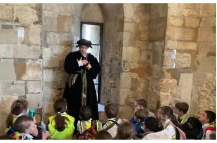 42 Y5 Tower of London Trip. Pupil group sat in front of adult in period dress.
