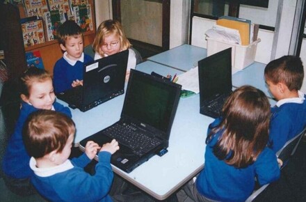 Dell Laptops 2002. Pupils in blue uniform working on laptops in group