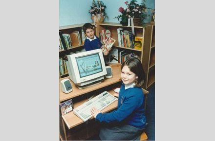 Library computer 1995. Pupils smiling using computer in library.