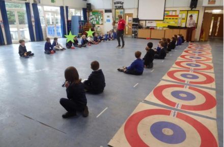 13 Kurling Kids Workshop. Pupils in hall sat beside targets.