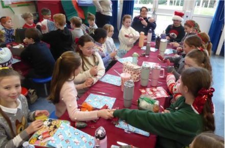 23 Christmas dinner. Group in festive attire sat at table eating and pulling crackers.