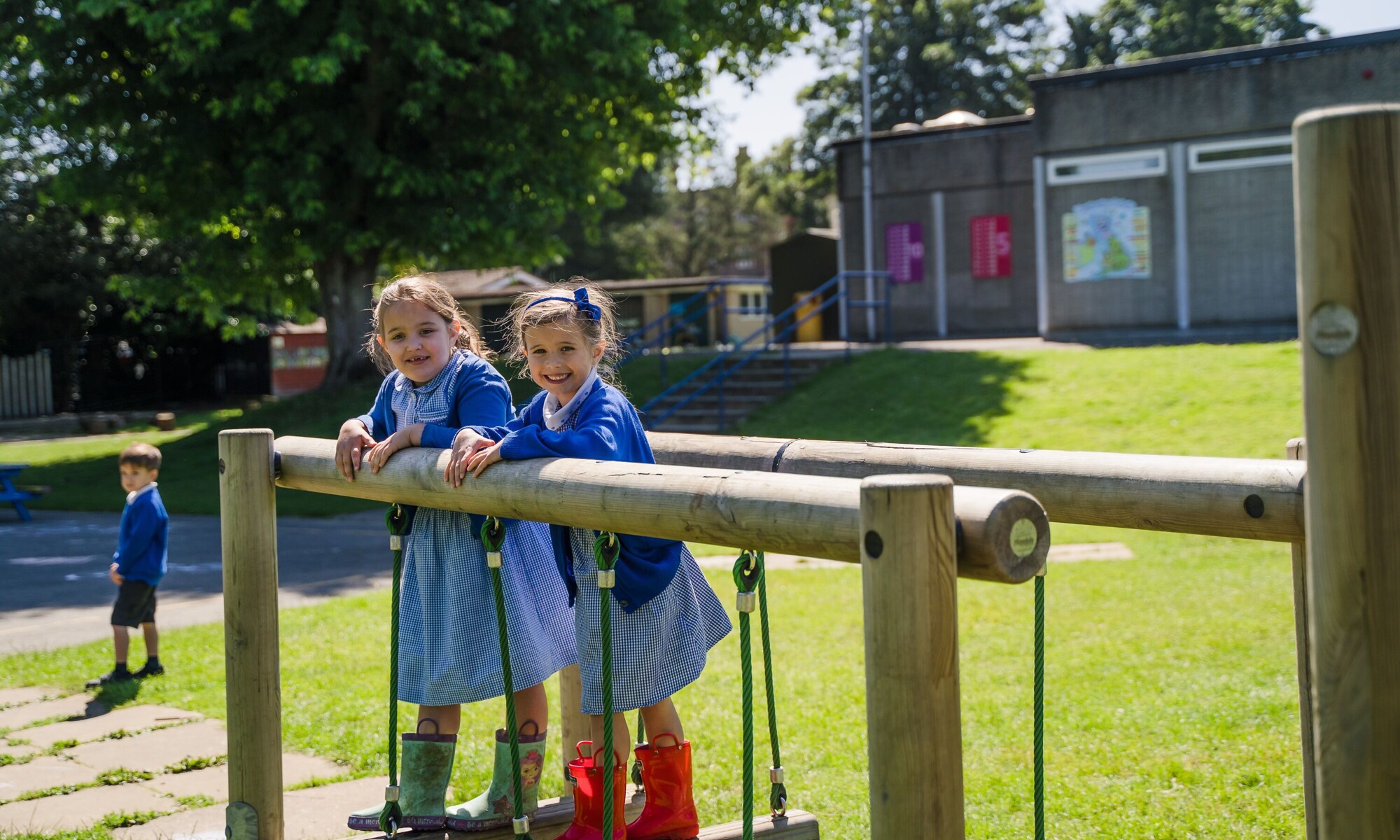 2 children on wooden play equipment in school grounds